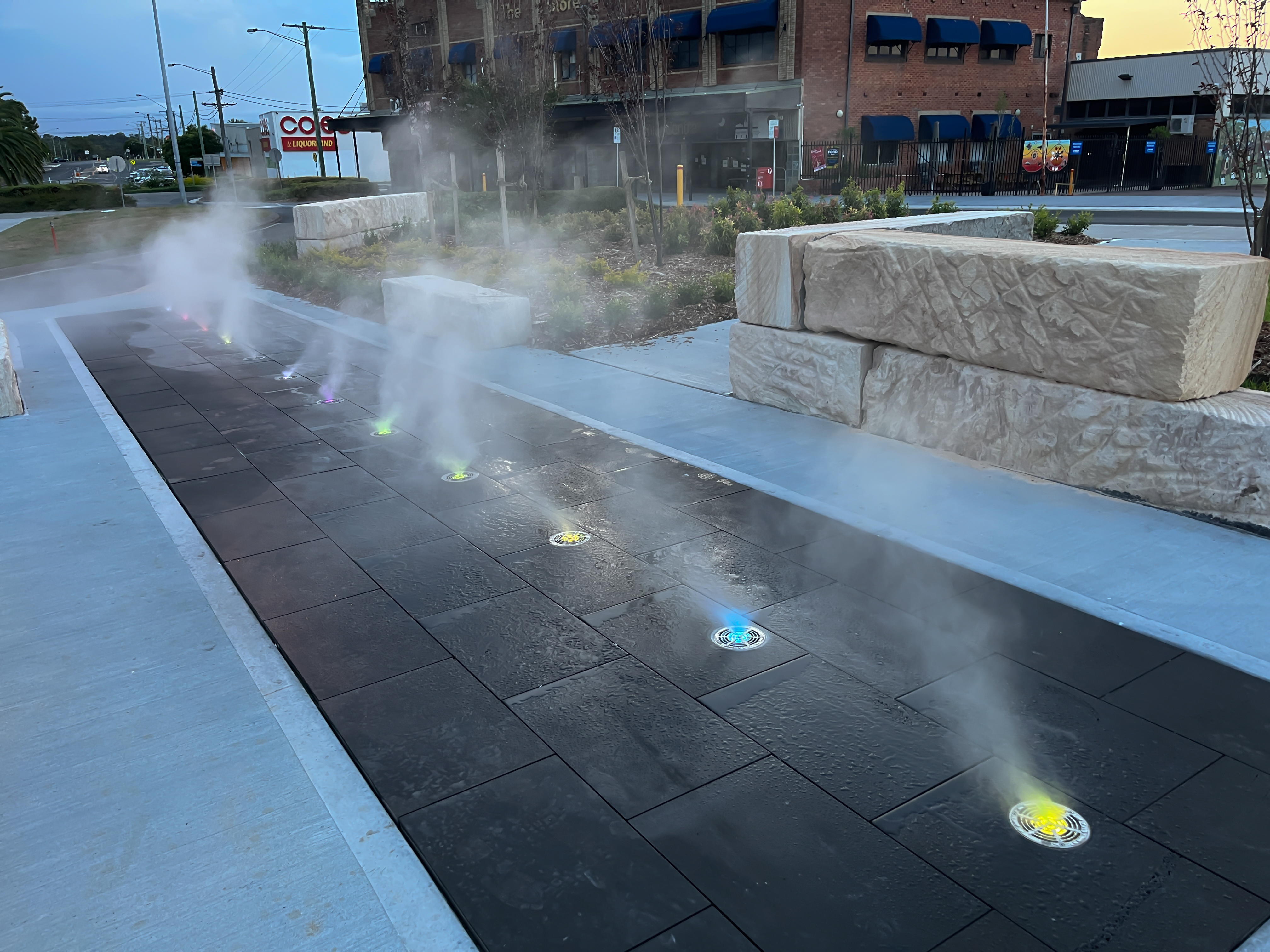 Flush-mount ground misting nozzles in public precinct pavers