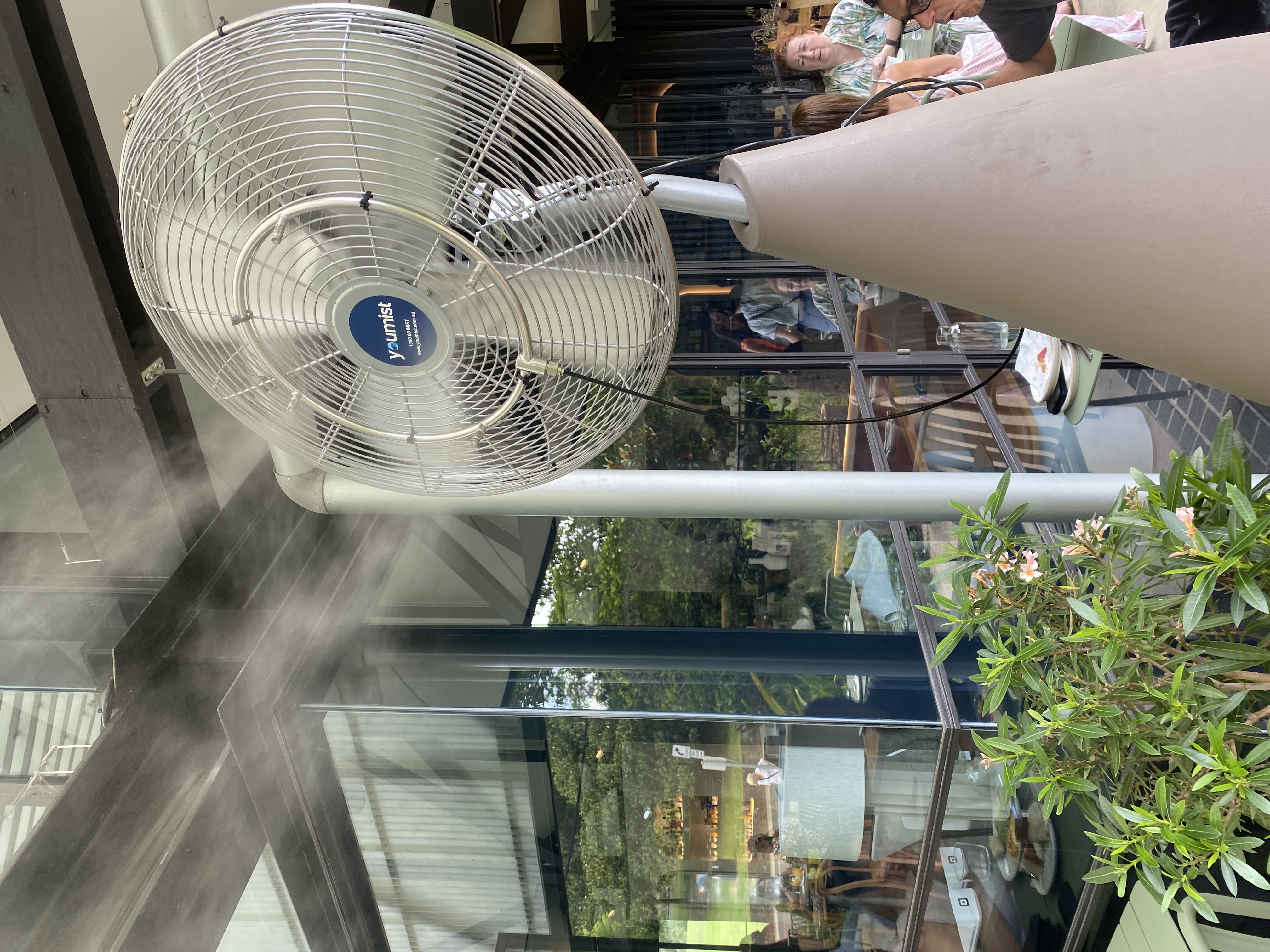 Wall-mounted misting fan under pergola